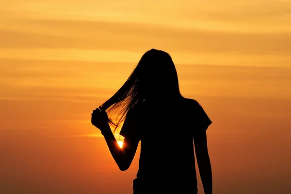 gün batımında saçını tutan kadın