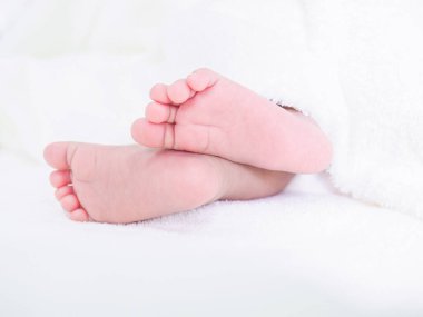 Yeni doğmuş bebek ayaklarını beyaz battaniyeyle kapat.