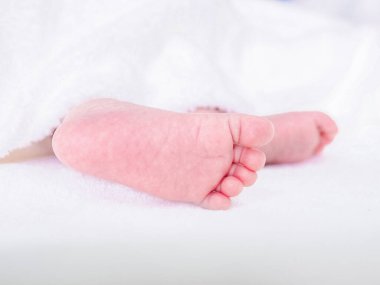 Yeni doğmuş bebek ayaklarını beyaz battaniyeyle kapat.