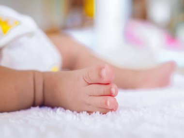 Yeni doğmuş bebek ayaklarını beyaz battaniyeyle kapat.