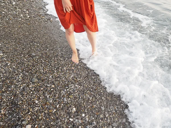 girl in barefoot at the shore with red skirt