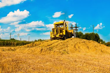 Hasat güneşli bir günde, bir alandaki sarı buldozer