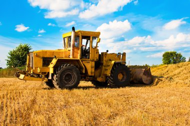 Hasat güneşli bir günde, bir alandaki sarı buldozer