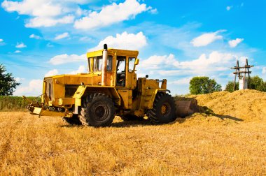 Hasat güneşli bir günde, bir alandaki sarı buldozer