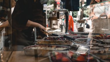 Pasta dükkanında çalışan bir kadın müşterinin önünde banka kasasında kredi kartı çalıyor.