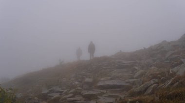 Sisteki bir adamın silueti. Dağlarda yoğun sis var. Ekstrem turizm, yürüyüş konsepti
