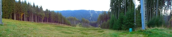 山地草甸的横向全景图像 夏天在别斯基底的滑雪坡翠绿的青草 背景是森林和小山 侧面是明亮的天空 — 图库照片