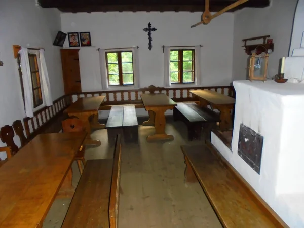 Roznov, Çek Cumhuriyeti - 08 04 2016: Tarihi evin içinde, beyaz duvarlı ve metal kapılı fırını olan sandalye ve banklı güzel ahşap masalar. Roznov kapsülü Radhostem Eflak açık hava müzesinde.