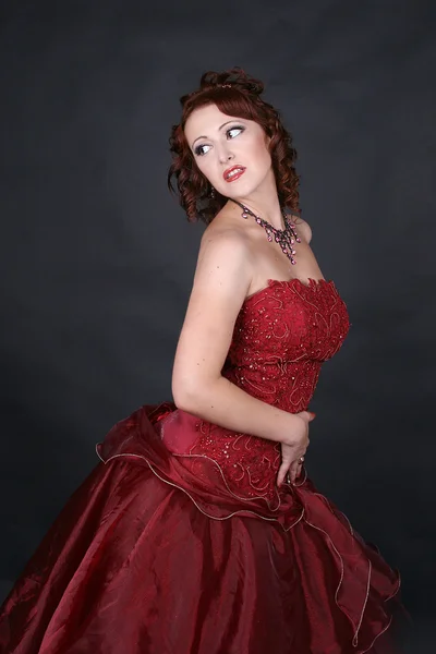 Red-haired beautiful girl dances a passionate Spanish dance studio on a dark background