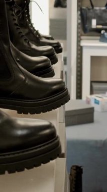 Ayakkabı mağazasındaki siyah deri çizmeler sıra sıra sergileniyor. Erkek kış ayakkabılarının ticari gösterisi..