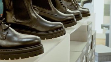Ayakkabı butiğinin beyaz raflarında kahverengi deri çizmeler. Sonbahar erkek ayakkabı koleksiyonuyla perakende satış..