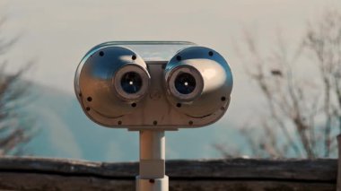 Çıplak ağaç dalları ve arka planda sisli dağlarla Alp Platformu 'nda sabit dürbünler.