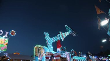 Gece lunaparkında neon ışığıyla dönen sarkaç. Dinamik yolculuk heyecan ve akşam eğlencesi atmosferi yaratır..