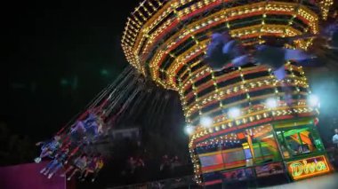 Parlak aydınlatmayla dekore edilmiş dönen zincir atlıkarınca gece görüşü. İtalyan eğlence parkında akşam eğlencesi atmosferi.