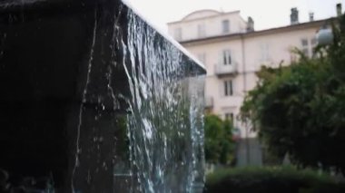 Süslü bir şehir çeşmesinden bronz heykellerle akan su akıntıları. Yaz boyunca bir Avrupa meydanında tarihi kent mimarisi.