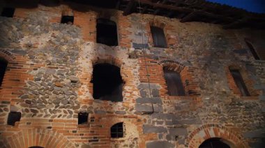 Antik taş kuleden heybetli bir manzara ve akşam ışığında İtalyan kalesinin duvarları..