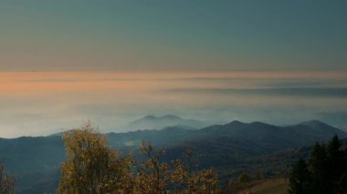 Şafak vakti yoğun beyaz bulutlarla kaplı bir şehir vadisinin hava manzarası. Sis altındaki kentsel alanı gösteren manzaralı dağ manzarası.