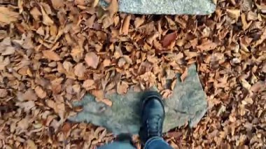 POV, Alp ormanlarındaki kuru sonbahar yapraklarıyla kaplı bir patikada bir kadının ayak izlerini takip ederken çekildi..