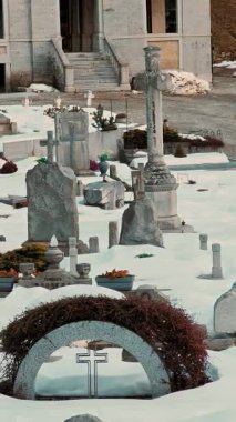 Kar kaplı mezar taşları ve bir kış günü antik bir İtalyan mezarlığında bulunan kemerli bir anıt. Mimari ayrıntılar.