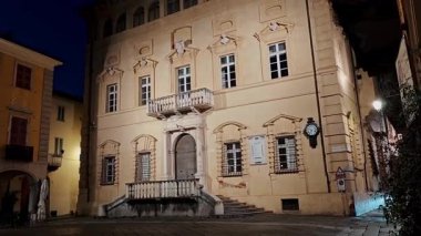 Şehir meydanında gece balkonlu tarihi sarayın etkileyici yüzü. Antik İtalyan kentinin mimari mirası.