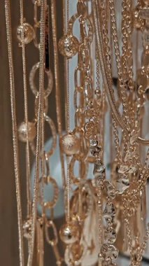 Stantta asılı büyük dekoratif unsurlara sahip narin kolyeler. Butikte kadınlar için çeşitli şık aksesuarlar..