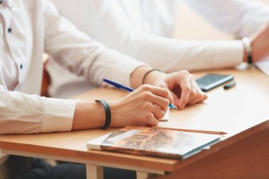 Not defterine kalem yazan bir erkek eli..