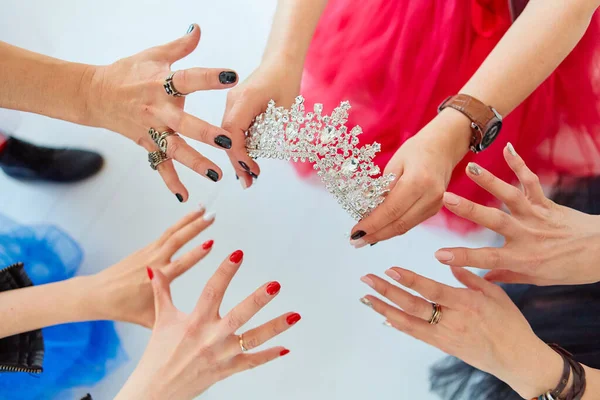 The girls \' hands reach for the crown. Who will be the Queen, the boss or the first beauty. The concept of competition and competition