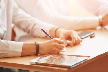 Not defterine kalem yazan erkeklerin elleri.