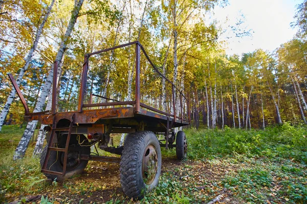 Traktorový přívěs. Starý přívěs sedí na zeleném trávníku. — Stock fotografie