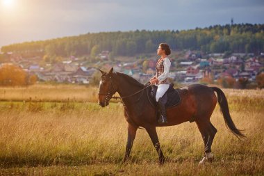 Gün batımında tarlalarda at süren genç bir kadın. Kapat..