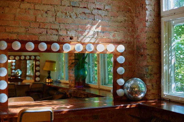 A makeup mirror with light bulbs on a brick wall background.