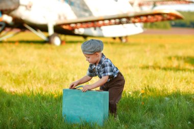 Pistte bavulu olan küçük, güzel bir çocuk yola çıkmaya hazır. Arka plandaki uçaklar.