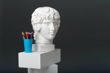 Antinous 'un alçı kafası bir bardaktaki kalem setinin yanında duruyor. Çizim ve yaratıcı faaliyetler kavramı.