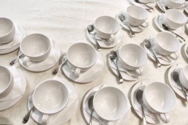 Bir sürü beyaz kahve fincanı. Çay ya da kahve için boş beyaz fincanlar halinde dizilmiş pek çok kişinin üst görüntüsü.