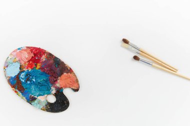 Beyaz arka planda farklı renklerde sanatçılar palet ve fırçalar