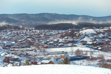 Rus Uralları 'nda kar fırtınası ile kaplı ahşap evleri olan kışın kırsal arazisi.
