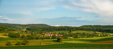 Güzel yeşil ve sarı tepeler. Gün batımı. Gölgeli panoramik manzara. Güney Fransa 'da bir çiftlik evi ve tarlası olan yaz kırsal arazisi.