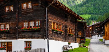 İsviçre Alpleri 'nde eski ahşap bir evde yaşıyormuş. Tipik bir ahşap ev köyünden güzel bir bahar zamanı dağlardaki yeşil çayır manzarası.