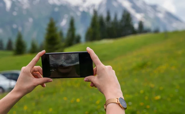 スイスアルプスを撮影するためにスマートフォンのカメラを使用して若い女性 女性旅行ブロガーは夏の旅行休暇中に携帯電話で写真を撮る — ストック写真