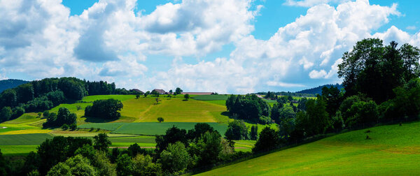 Idyllic rural view of farmland in the beautiful surroundings near Basel, Switzerland, Europe, close to the France and German borders. Fields and wonderful blue sky, panoramic view with shadows.