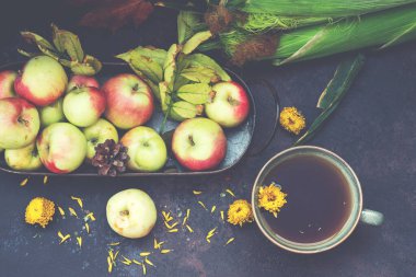 Sonbahar, sonbahar yaprakları, çiçekler, elmalar ve fincan çay. Ahşap kırsal arka planda sonbahar çiftliği hasadı. Tonu ayarlanmış resim.