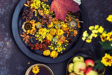 Sonbahar, sonbahar yaprakları, çiçekler, elmalar ve fincan çay. Ahşap kırsal arka planda sonbahar çiftliği hasadı. Tonu ayarlanmış resim.