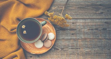 Sonbahar, sonbahar yaprakları, sıcak bir fincan çay ve ahşap masa zemininde sıcak bir eşarp. Mevsimlik, sabah çayı, pazar günü bahçede dinlenmek ve sakin bir hayat..