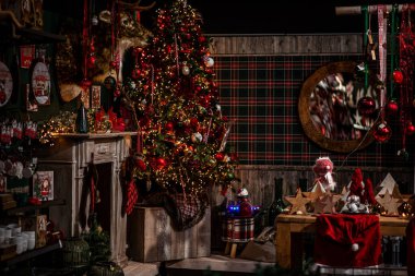 Ağaç, hediye ve şömineli Noel sahnesi. Noel, Yeni Yıl dekore edilmiş çelenk ve toplarla süslenmiş köknar ağacı, karanlık çekmece ve geyik figürleri. Noel pazarı, kış, yeni yıl konsepti.