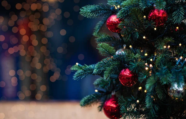 Noel arkaplanda köknar dalları ve Noel baloları var. Bulanık arka planda dekore edilmiş Noel ağacı.