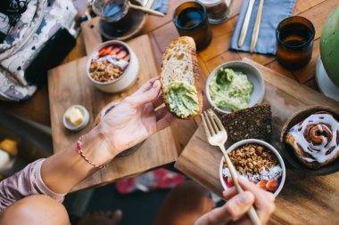 Yukarıdaki ekin bayanlarından kahvaltıda atıştırmalık ekmek kasesi ve tarçınlı çörek yerken kafeteryadaki ahşap masada oturuyorlar.