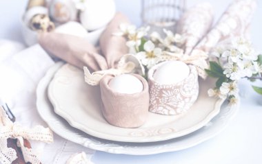 Paskalya yumurtaları ve bahar çiçekleriyle paskalya arkaplanı. Paskalya kompozisyonu, beyaz plakalı yumurtalar. Paskalya tavşanı peçete hediye yumurta paketleme fikri.