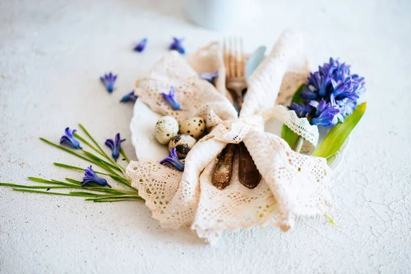 Vintage easter background. Dinner plate setting with vintage napkin and old silverware. Easter eggs and spring flowers.