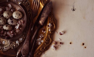 Yukarıdan klasik ya da kırsal paskalya sofrası seti. Tabak, çatal bıçak takımı, yumurtalar ve kırsal kesimde doğal bahar dalı. Köy tarzı. Uzayı kopyala Tonu ayarlanmış resim.