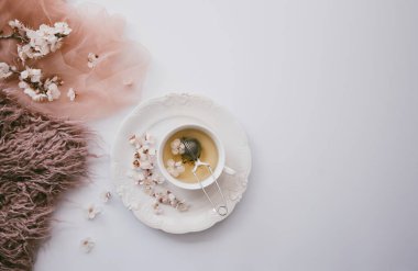 Elma ağacı çiçekli bir fincan çay. Beyaz bir fincanda, çiçekli beyaz bir tahta masada bitki çayı. Çay seremonisi. Uzayı kopyala Seçici odak.